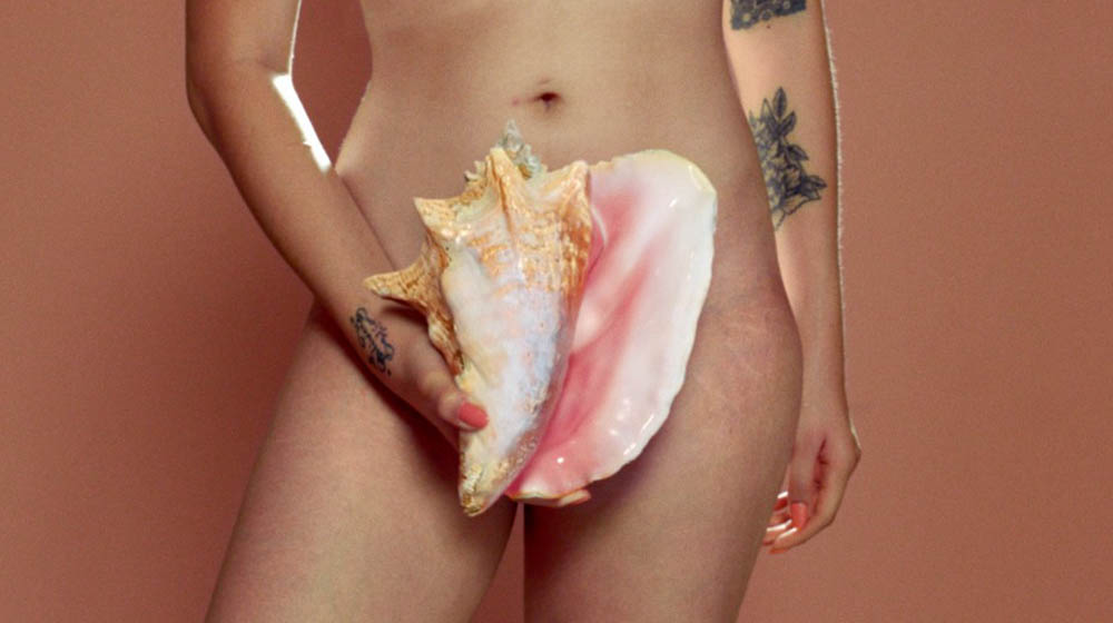 Naked woman holding a large shell to represent her vulva, shown at the start of the Libresse Viva La Vulva video