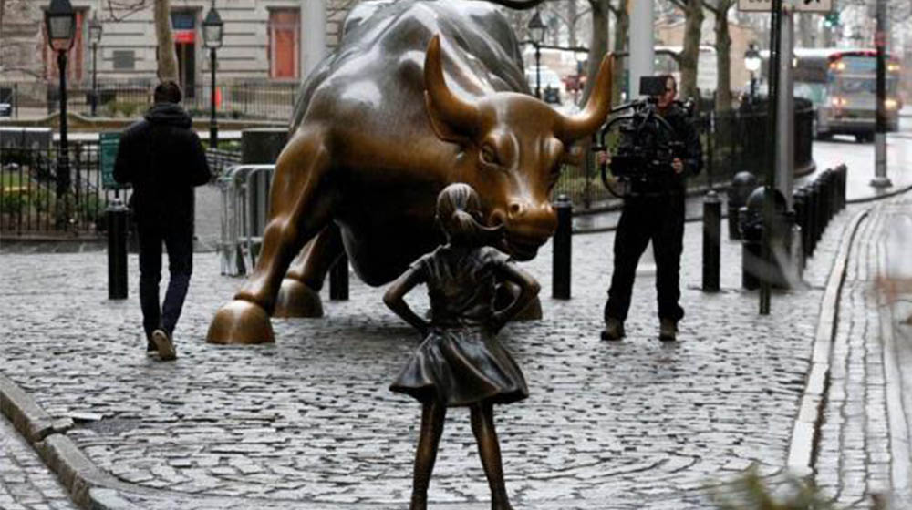 Fearless Girl statue facing a statue of a charging bull in Wall Street, New York